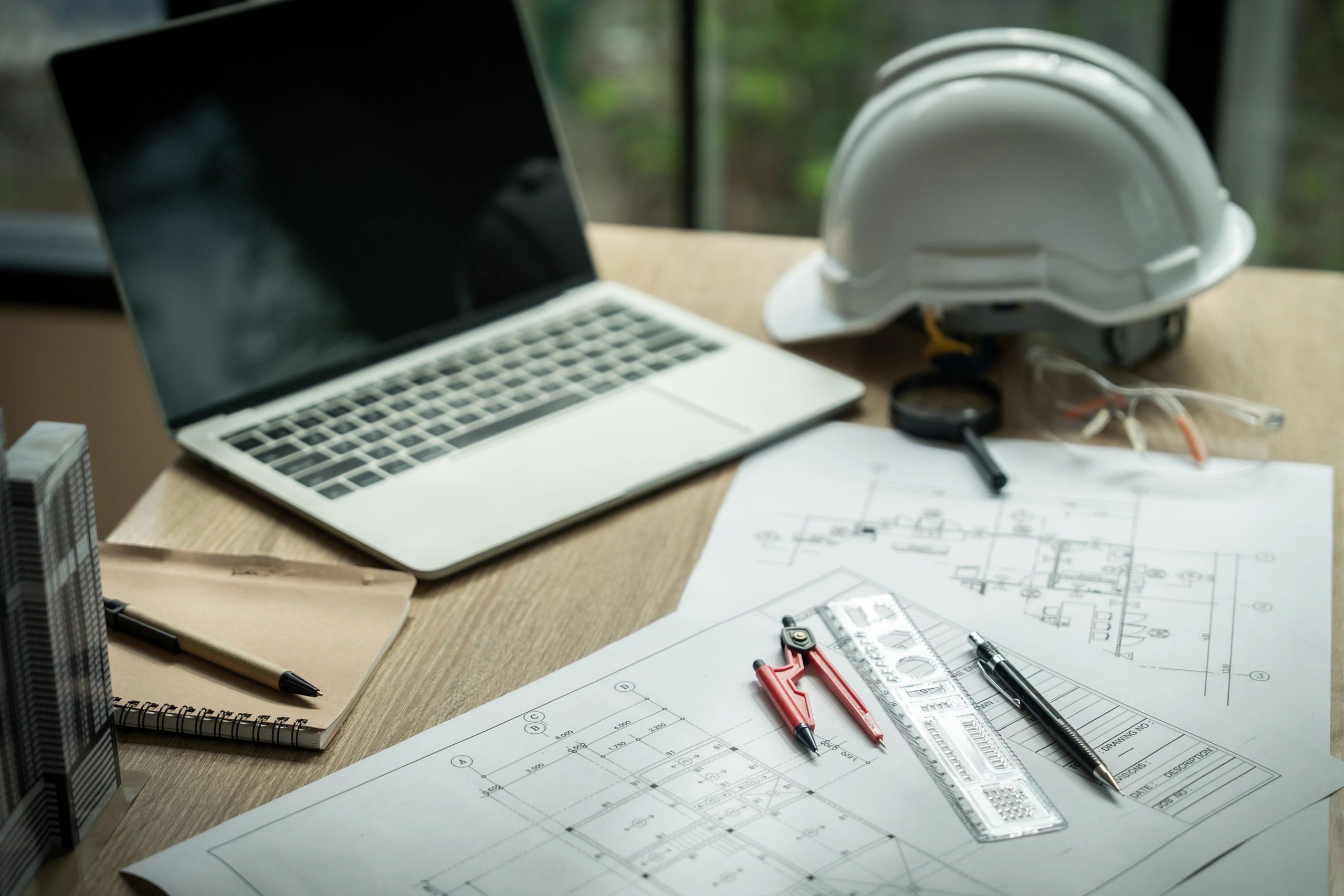 Drafting tools and laptop on a desk with plans