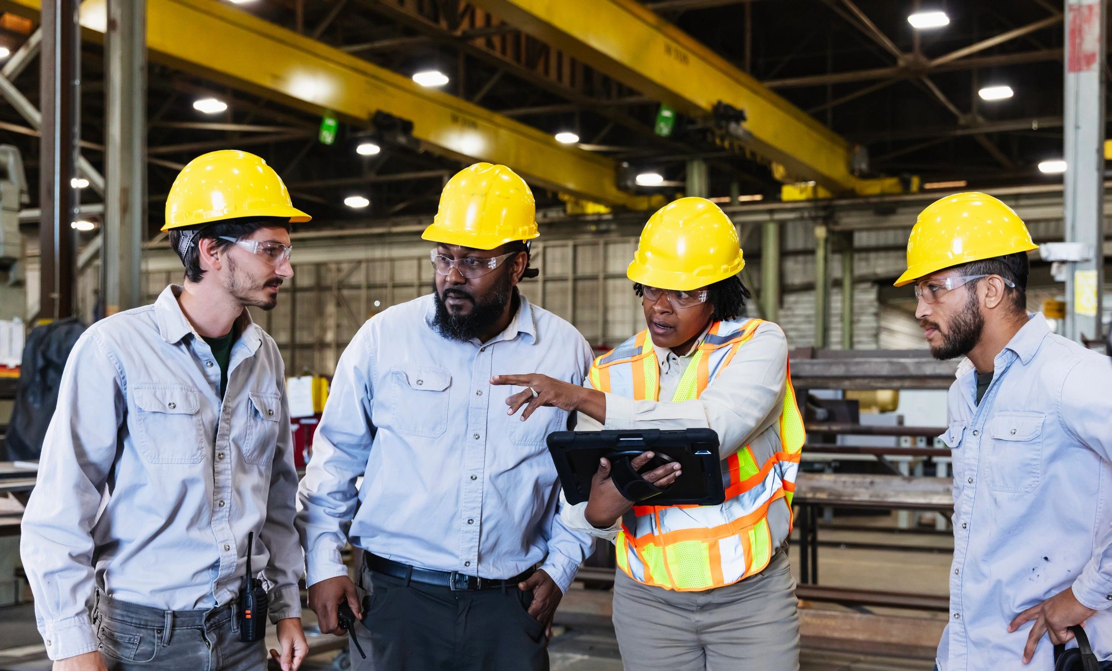 Engineering team coordinating on a factory floor with a tablet